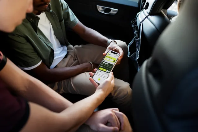 Dos personas consultan la app La Rueda en un móvil dentro de un coche