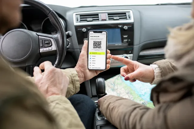 Dos personas consultan en un móvil un código QR de La Rueda dentro de un coche